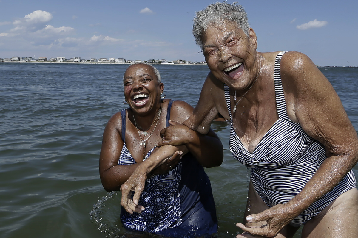 Traci Scott (left) and Delores Mitchell hold on to each other and laugh after they both went under the water at the Caspian Avenue beach in Atlantic City, where everybody is family.
