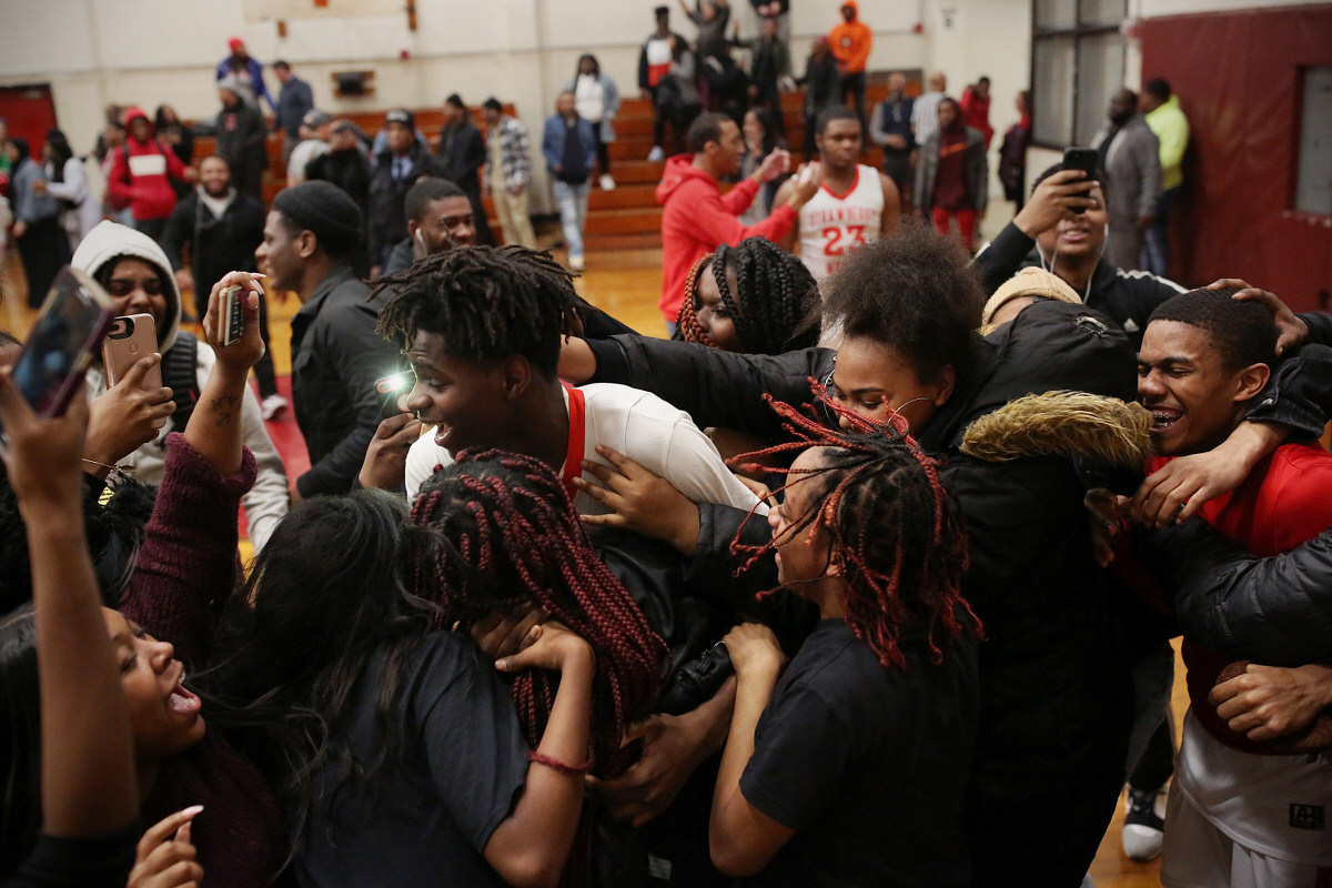 Strawberry Mansion students storm the school’s court in celebration after the team won its first-round Public League playoff game against Overbrook in February.